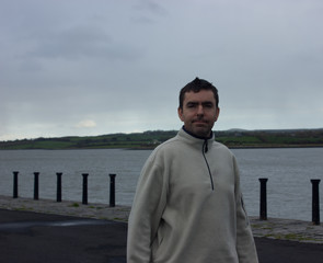 man to the waist is standing on the pier in home clothes