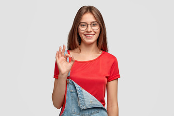 Photo of cheerful young woman shows zero or okay gesture, shows her approval, likes something,...