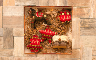 Vintage rag knitted Christmas toys in a box with thatched bedding and lights. Retro style. Isolate on old wooden background.