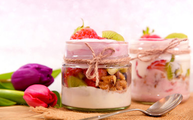Mixed fruits and walnuts yogurt in glass with bow tie on Bokeh background..Breakfast with many kind of fruits and yogurt.