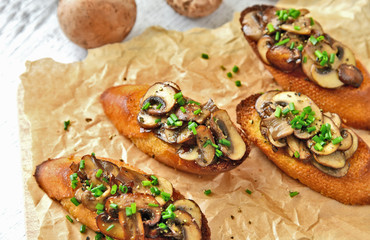 Champignon or brown cap mushroom Crostini on brown paper and wooden board.