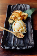 Warabi Mochi served with a scoop of vanilla ice cream that topping with caramel served in black plate.