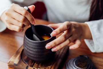 Fototapeta na wymiar Japanese Caramel Pudding served in black ceramic cup that scoop soft pudding by woman hand.