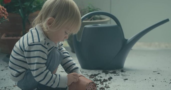 Little toddler playing with dirt on a balcony