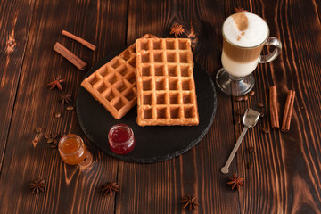 Tasty fresh Vienna wafers, jam and cup of coffee on a dark wooden background