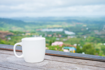 White coffee cup in outdoor coffee shop with beautiful mountain view in morning