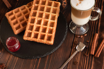Tasty fresh Vienna wafers, jam and cup of coffee on a dark wooden background