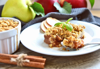 Apple crumble on with dish with spoon and fresh green and red apple with cinnamon stick on wooden floor. Easy and Basic dessert menu.