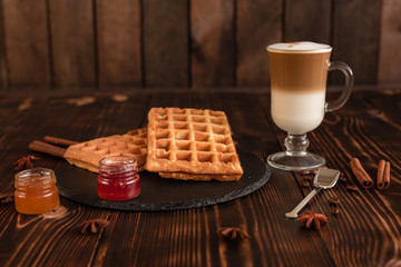 Tasty fresh Vienna wafers, jam and cup of coffee on a dark wooden background