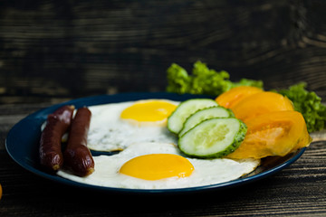 Homemade delicious breakfast with sunny side up fried egg, sausage, tomatos in top view