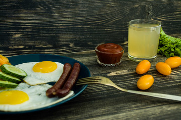 Homemade delicious breakfast with sunny side up fried egg, sausage, tomatos in top view