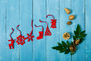 Christmas decoration background with holly leaves and red felt ornaments on old blue wooden table