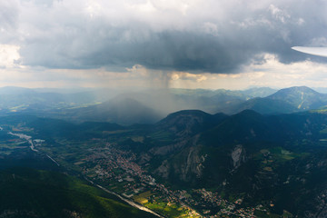 Obraz premium Luftaufnahme aus einem Segelflugzeug mit Blick über eine Berglandschaft im Regen