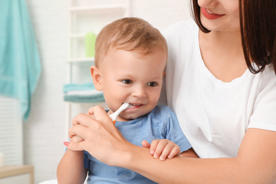 Woman and her son with toothbrush on blurred background