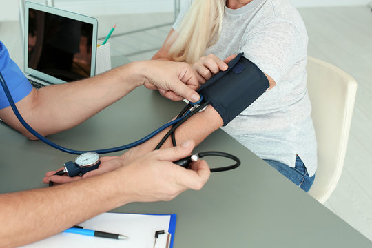 Close up view of medical assistant measuring female patient blood pressure in clinic