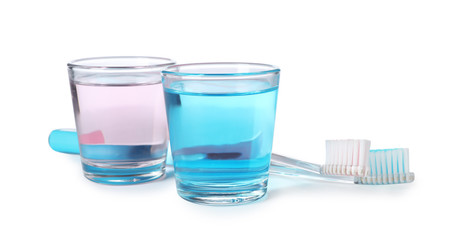 Glasses with mouthwash and toothbrushes on white background. Teeth hygiene