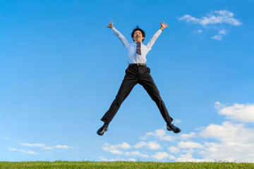 Fototapeta na wymiar 青空をバックにバンザイしながらジャンプするスーツ姿の若いビジネスマン1人。成功・達成・成就・元気・健康イメージ