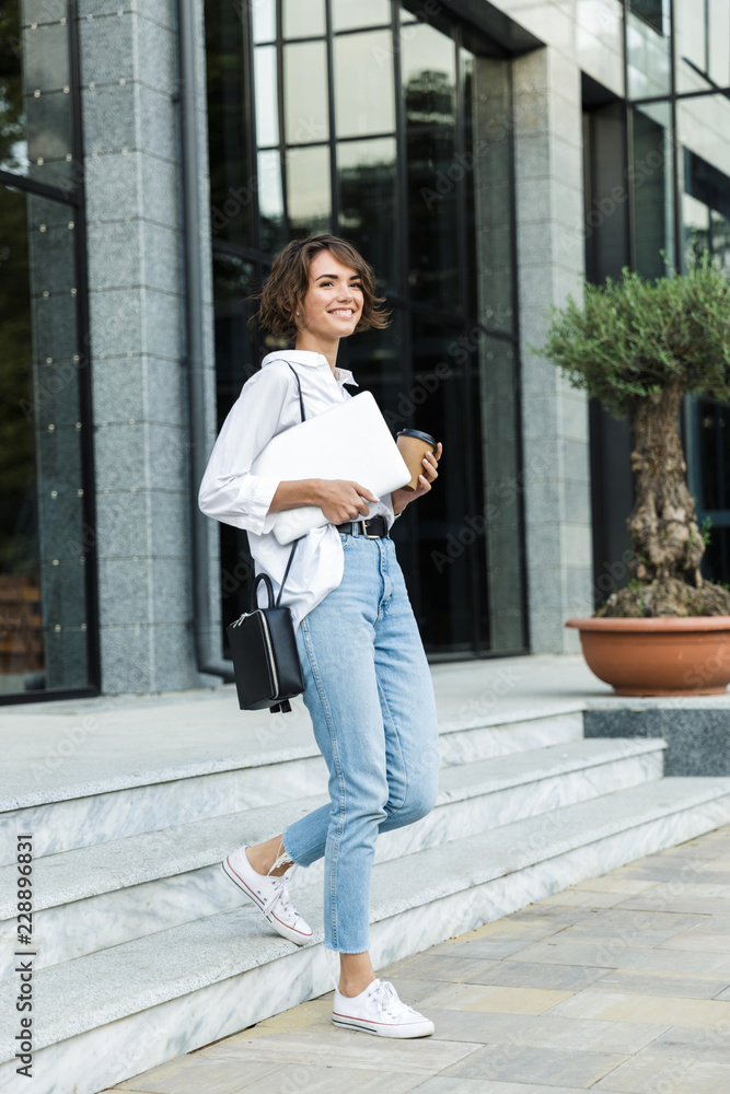 Wall mural Lovely young woman walking outdoors at the street