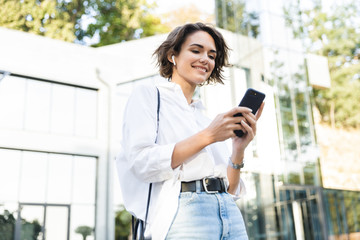 Beautiful young woman in earphones standing