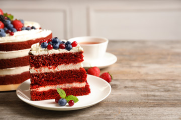 Plate with piece of delicious homemade red velvet cake on table. Space for text