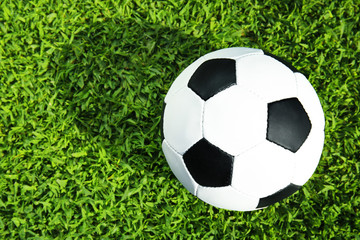 Soccer ball on fresh green football field grass, top view. Space for text