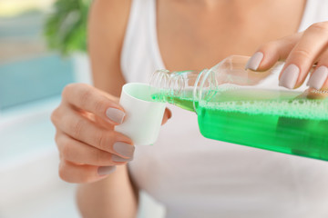 Woman pouring mouthwash from bottle into cap, closeup. Teeth care - obrazy, fototapety, plakaty