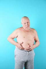 Naklejka premium Fat senior man on color background. Weight loss