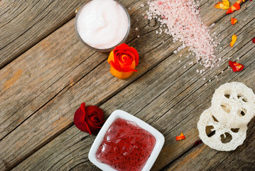 facial mask and moisturizer with roses on weathered wooden