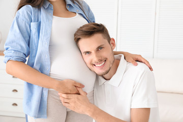 Fototapeta premium Young husband listening to his beautiful pregnant wife's tummy