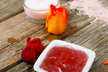 facial mask and moisturizer with roses on weathered wooden