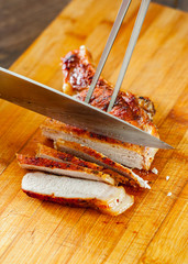 Fototapeta premium Chef hand with knife cutting meat on wooden board.