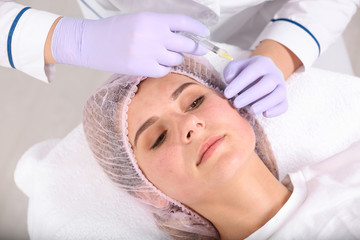 Fototapeta na wymiar Woman undergoing face biorevitalization procedure in salon. Cosmetic treatment