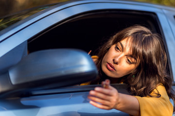 Fototapeta na wymiar Attractive woman applying lipstick in a car