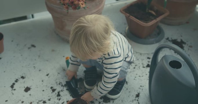 Little toddler gardening on balcony