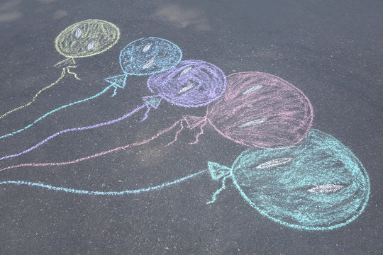Child's chalk drawing of balloons on asphalt