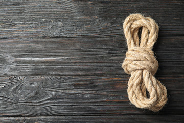 Fototapeta na wymiar Bundle of natural hemp rope on wooden background, top view with space for text