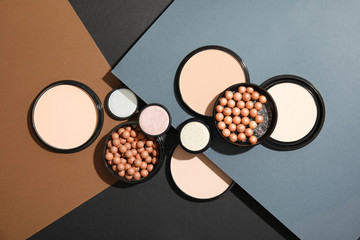 Flat lay composition with various makeup face powders on color background