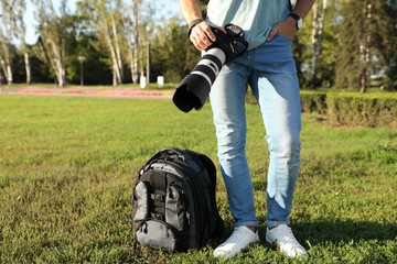 Young male photographer holding professional camera outdoors