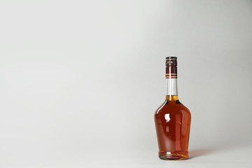 Bottle of alcoholic drink on grey background. Space for text