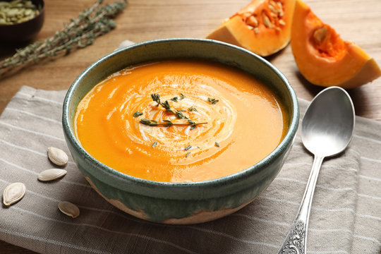 Delicious pumpkin cream soup in bowl on wooden table