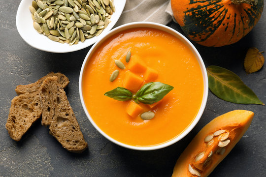 Flat lay composition with bowl of pumpkin soup on gray background