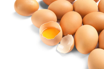 Cracked and whole chicken eggs on white background