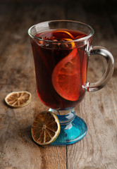 Glass with red mulled wine on wooden table