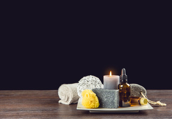 Man spa relaxation concept. Different day spa products on white ceramic tray on wooden table, dark black background.