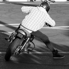 fashionably dressed biker shows tricks on a vintage motorcycle