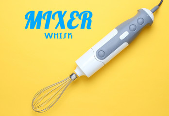 Electric hand blender whisk on yellow background. Top view, minimalism.
