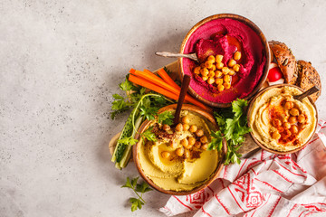Different hummus bowls. Chickpea hummus, avocado hummus and beetroot hummus, top view.