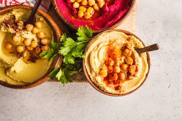 Different hummus bowls. Chickpea hummus, avocado hummus and beetroot hummus, top view.