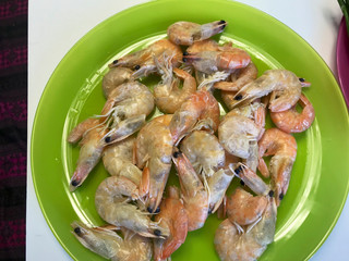 Boiled shrimps lie in a plate. Steam comes from them.