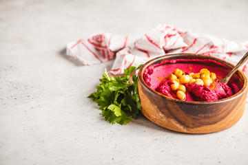Beet hummus in a wooden bowl with vegetables, copy space.